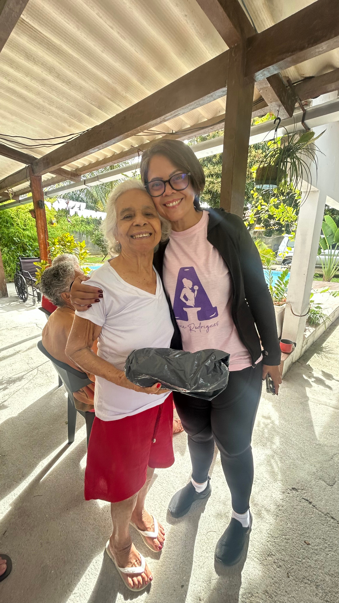 Cuidadora da Casa Aurora abraçando carinhosamente uma residente sorrindo