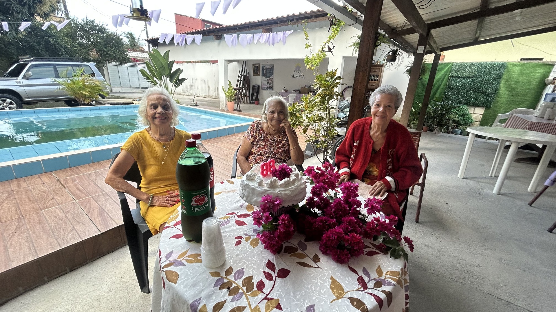 Residentes da Casa Aurora celebrando aniversário com bolo à beira da piscina
